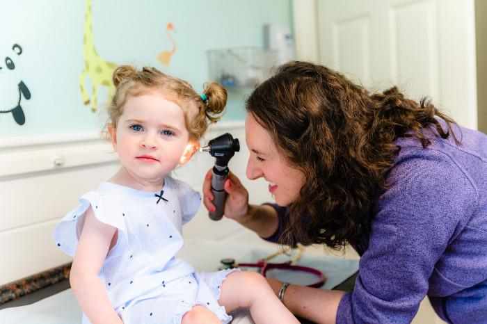 a provider examining the ear of a young girl